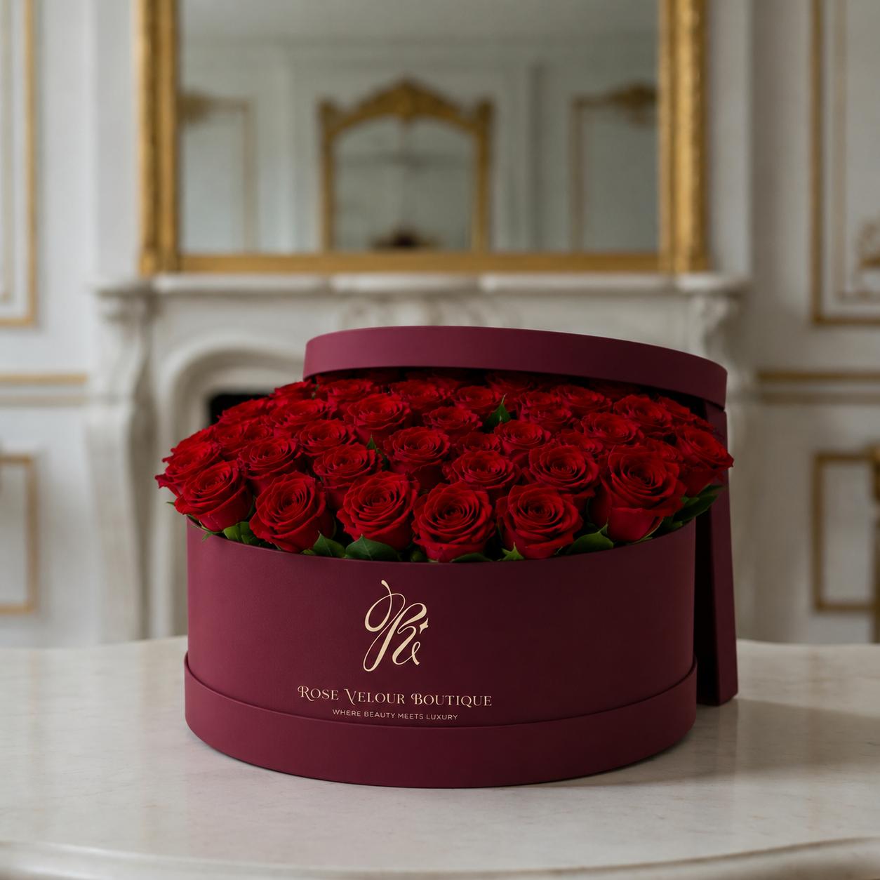 The Velour Signature — burgundy round hatbox of red roses on marble